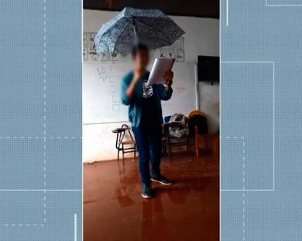 Estudante usa guarda-chuva durante aula por causa de goteiras em escola após chuva no sul da Bahia